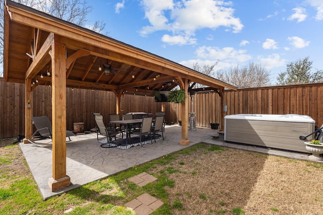 view of patio / terrace featuring a ceiling fan, a gazebo, a fenced backyard, and a hot tub