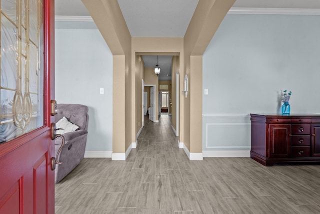 foyer featuring crown molding, baseboards, and light wood finished floors