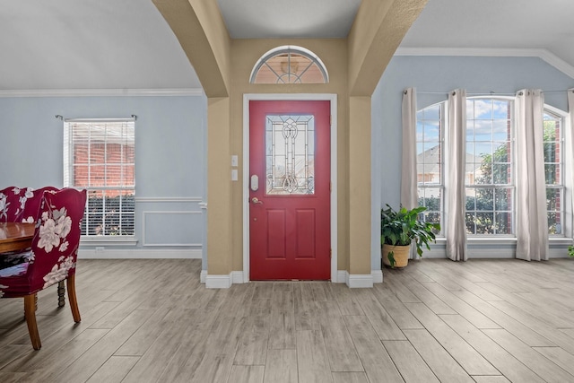 entrance foyer featuring ornamental molding, wood finished floors, arched walkways, and a healthy amount of sunlight