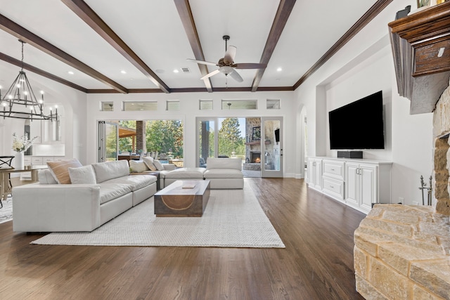 living area featuring dark wood-style floors, visible vents, a lit fireplace, beamed ceiling, and ceiling fan with notable chandelier