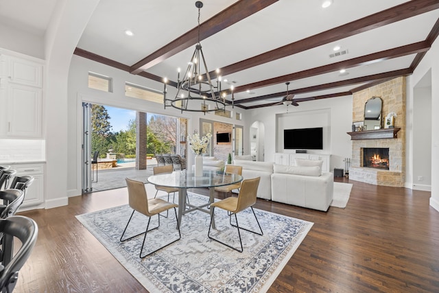 dining space featuring dark wood-type flooring, a fireplace, arched walkways, and visible vents