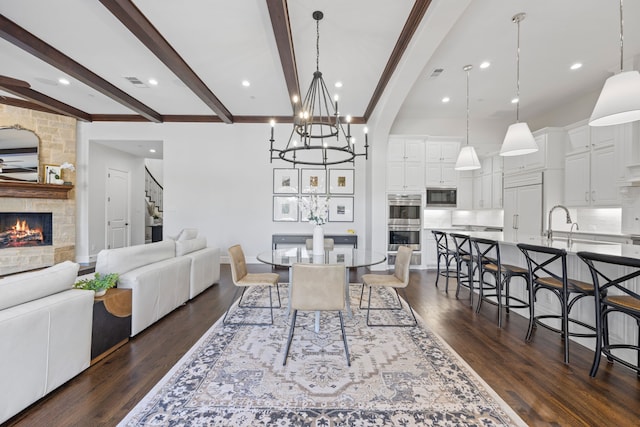 dining room featuring beamed ceiling, a fireplace, dark wood-type flooring, and visible vents