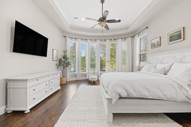 bedroom featuring dark wood-style floors, crown molding, a raised ceiling, and baseboards