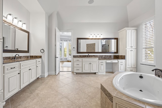 bathroom featuring tile patterned flooring, a jetted tub, two vanities, and a sink