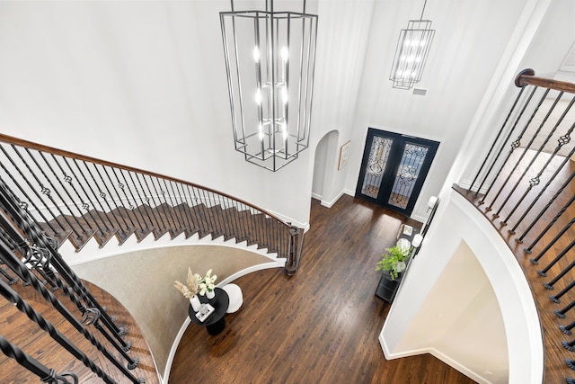 entrance foyer with arched walkways, stairway, french doors, and wood finished floors