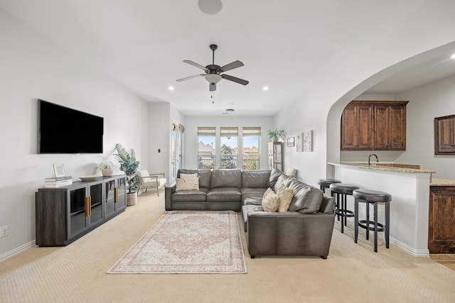 living area with arched walkways, recessed lighting, light carpet, and baseboards