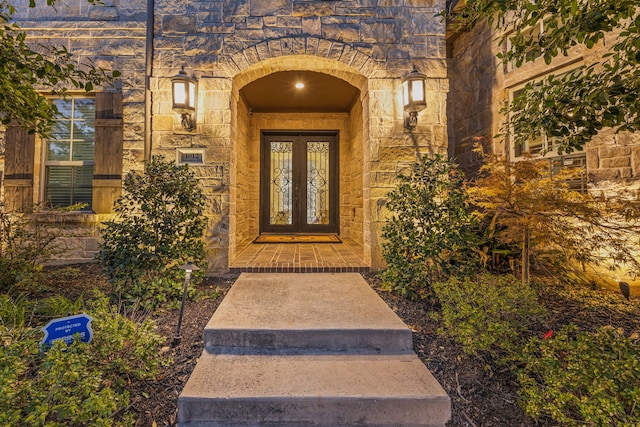 view of exterior entry with stone siding and french doors