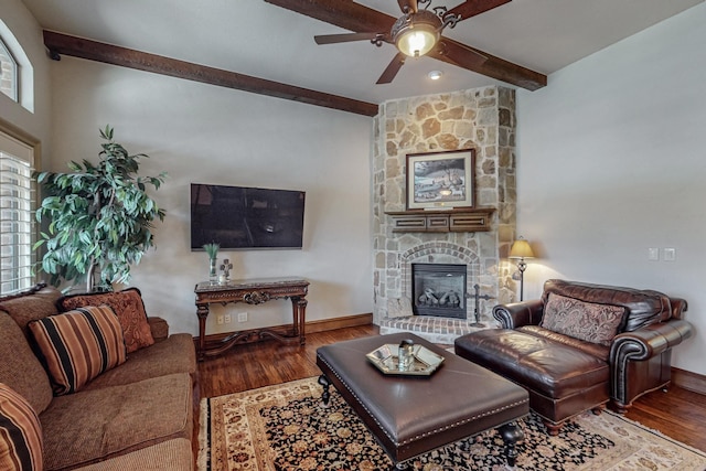 living room with baseboards, beam ceiling, a fireplace, wood finished floors, and a ceiling fan