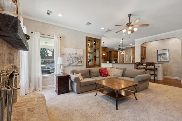 living area with visible vents, baseboards, ornamental molding, arched walkways, and a ceiling fan