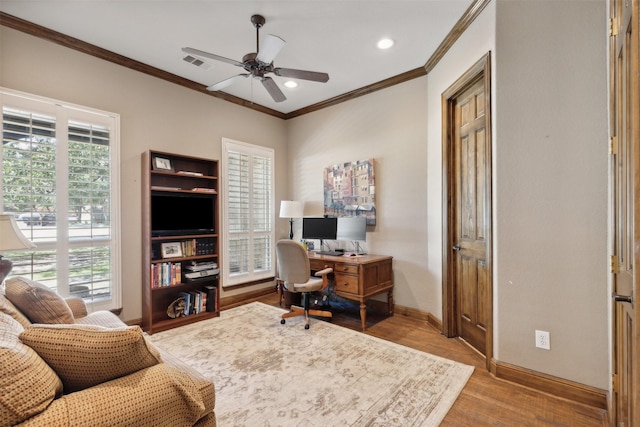 office space featuring wood finished floors, crown molding, a healthy amount of sunlight, and visible vents