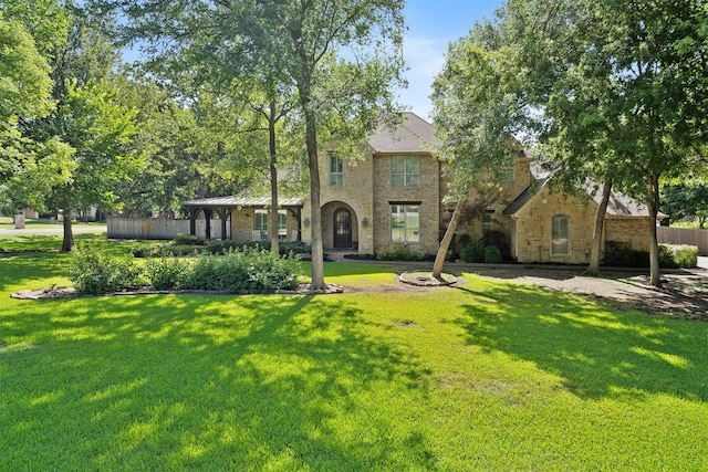 tudor house featuring a front lawn and fence