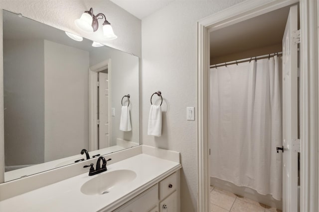 full bathroom featuring tile patterned flooring, vanity, and a textured wall