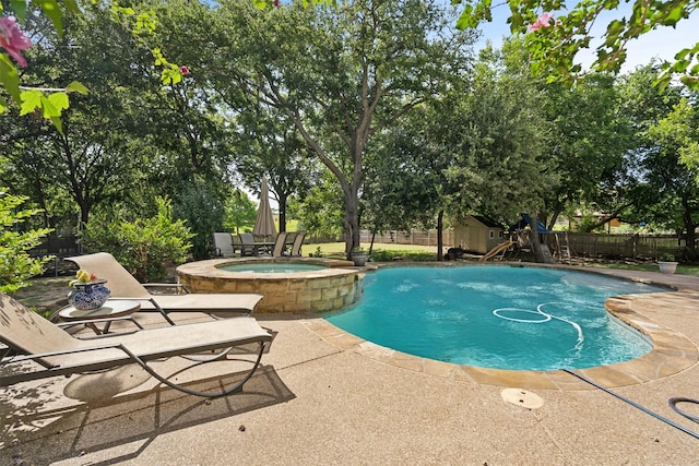 view of swimming pool featuring a patio, a playground, fence, and a pool with connected hot tub