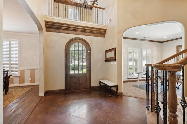 entrance foyer featuring arched walkways, a high ceiling, and ornamental molding