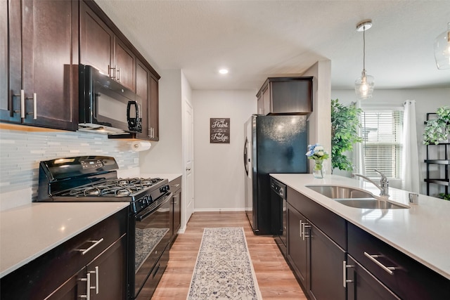 kitchen featuring black appliances, light countertops, light wood-type flooring, and a sink