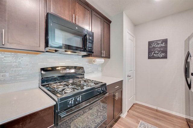 kitchen with tasteful backsplash, dark brown cabinetry, light countertops, light wood-style flooring, and black appliances