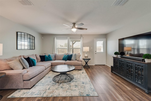 living area with visible vents, baseboards, a ceiling fan, and wood finished floors