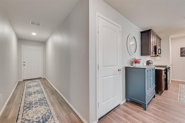 corridor with visible vents, baseboards, and light wood-style floors