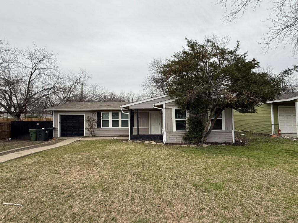 view of front of home with driveway, an attached garage, a front lawn, and fence