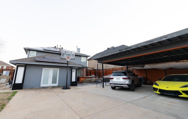 rear view of house featuring french doors and solar panels