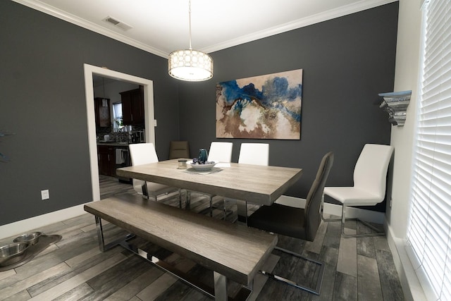 dining room with crown molding, wood finished floors, baseboards, and visible vents