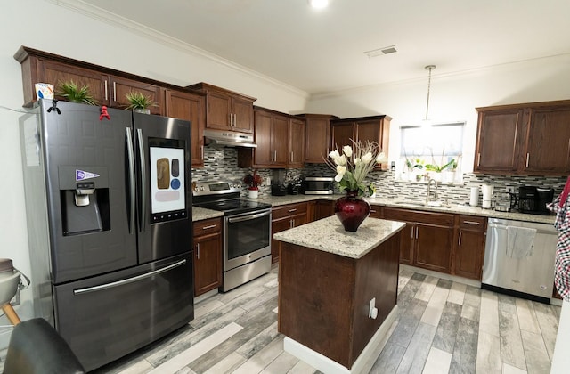 kitchen featuring visible vents, a sink, under cabinet range hood, stainless steel appliances, and crown molding