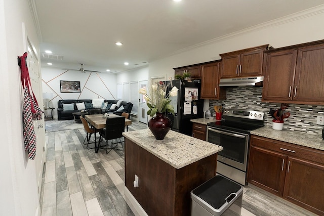 kitchen with a kitchen island, stainless steel electric stove, freestanding refrigerator, decorative backsplash, and under cabinet range hood