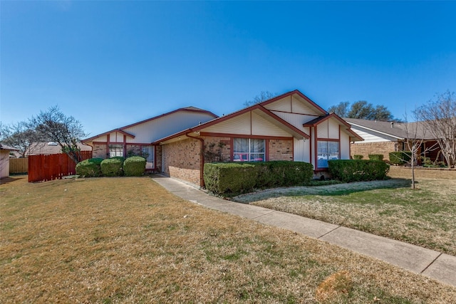 view of front of property with a front lawn, fence, and brick siding