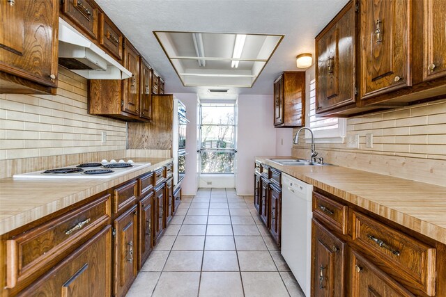 kitchen featuring a sink, white appliances, butcher block counters, and light tile patterned floors