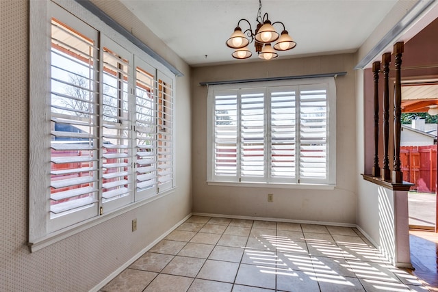 unfurnished dining area featuring an inviting chandelier, light tile patterned floors, and baseboards