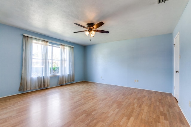 spare room with a textured ceiling, light wood-type flooring, and a ceiling fan