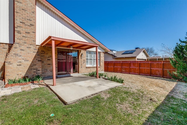 exterior space featuring a yard, a patio, brick siding, and fence