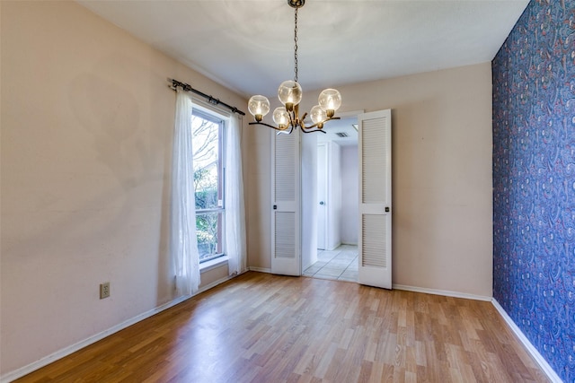 unfurnished dining area with a chandelier, visible vents, baseboards, and wood finished floors