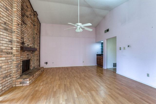 unfurnished living room with visible vents, high vaulted ceiling, a ceiling fan, wood finished floors, and a fireplace