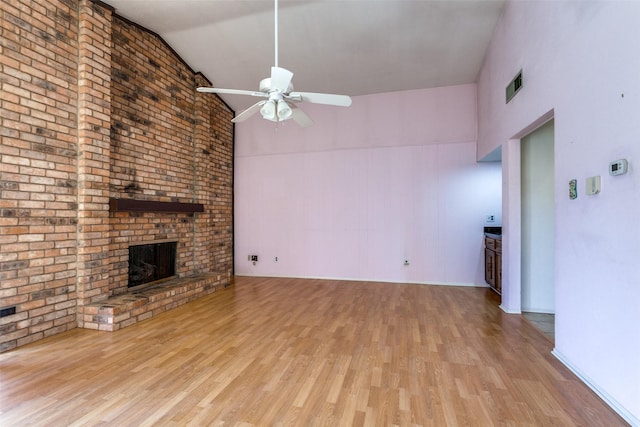 unfurnished living room featuring a ceiling fan, a brick fireplace, wood finished floors, and visible vents