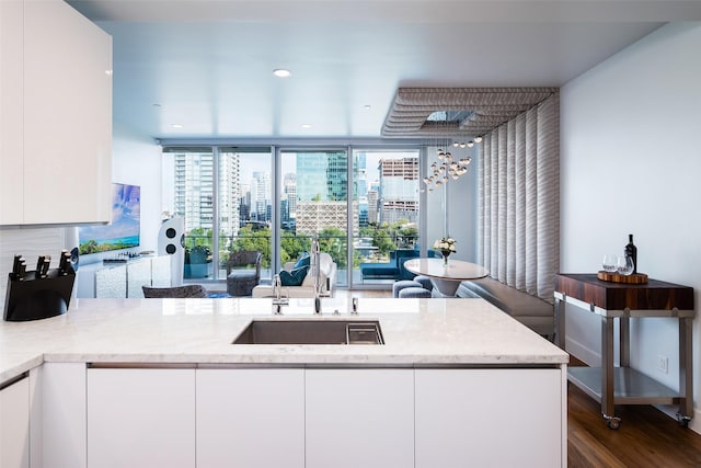 kitchen with light stone countertops, modern cabinets, white cabinets, and a sink
