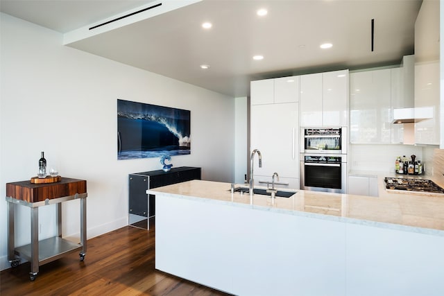 kitchen with recessed lighting, stainless steel appliances, a sink, dark wood-type flooring, and a peninsula