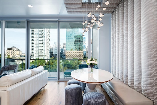 dining space featuring a city view, wood finished floors, floor to ceiling windows, and a notable chandelier