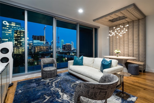 living room featuring a chandelier, wood finished floors, a view of city, and a wall of windows