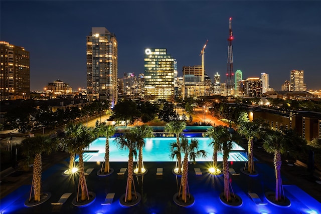 pool at twilight featuring a view of city lights