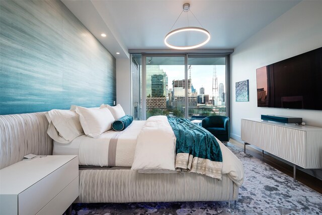 bedroom with recessed lighting, wood finished floors, baseboards, expansive windows, and access to outside
