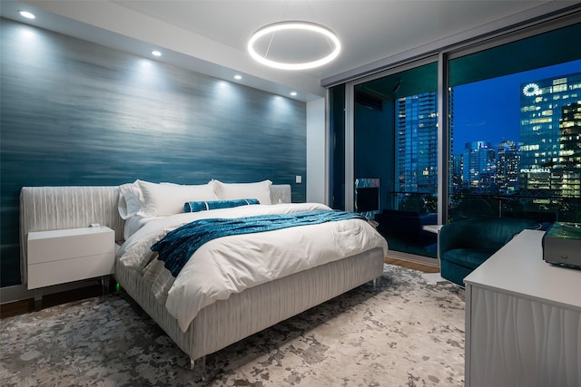 bedroom with recessed lighting, expansive windows, wood finished floors, and a view of city