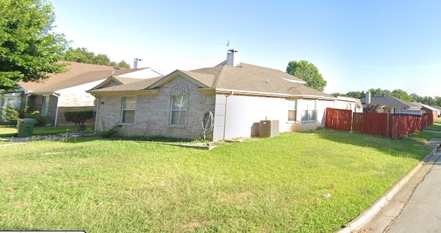 back of house featuring fence, a yard, cooling unit, brick siding, and a chimney