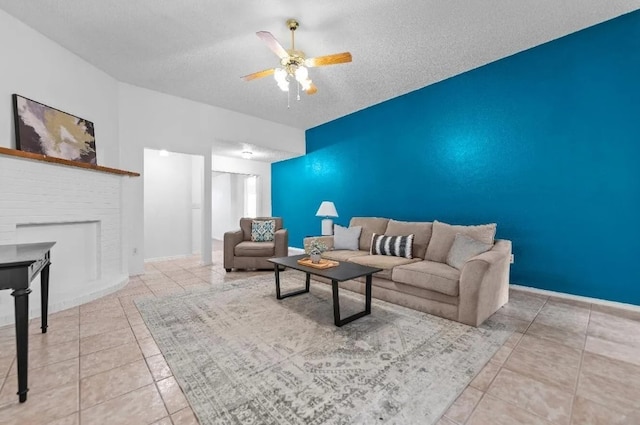 tiled living room featuring baseboards, a textured ceiling, ceiling fan, and a fireplace