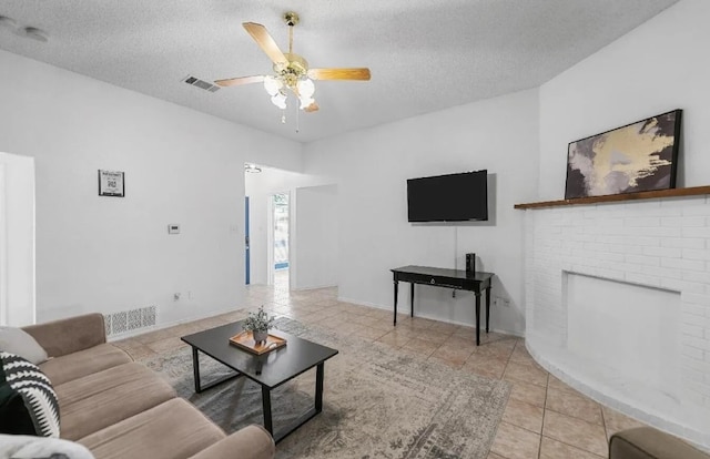 living room with tile patterned floors, visible vents, a textured ceiling, and a ceiling fan