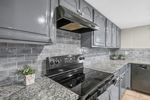 kitchen with gray cabinetry, light stone countertops, under cabinet range hood, decorative backsplash, and black appliances