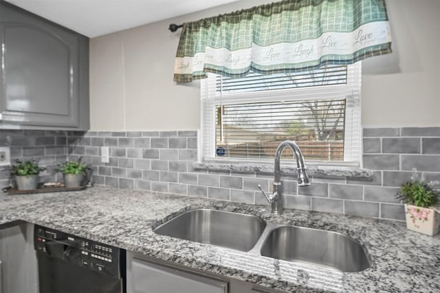 kitchen with tasteful backsplash, dishwasher, light stone counters, gray cabinets, and a sink