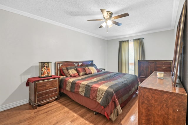 bedroom with ceiling fan, a textured ceiling, ornamental molding, and light wood finished floors