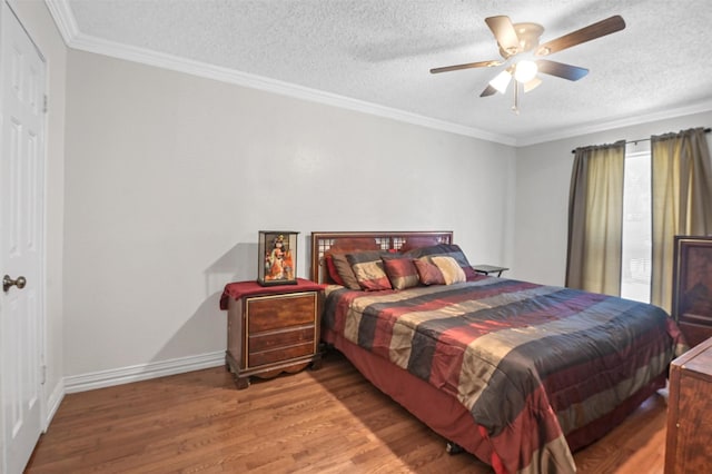 bedroom featuring a textured ceiling, crown molding, baseboards, and wood finished floors