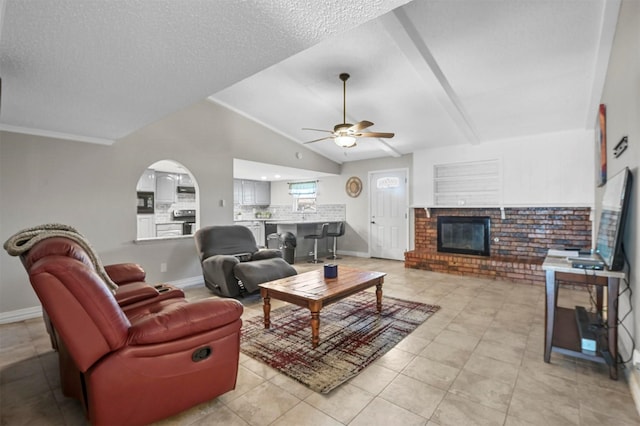 living area with baseboards, lofted ceiling, ceiling fan, and a fireplace